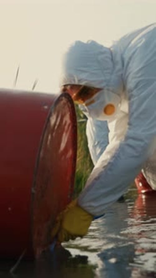 Hazmat Team Testing River Water Next to Barrels