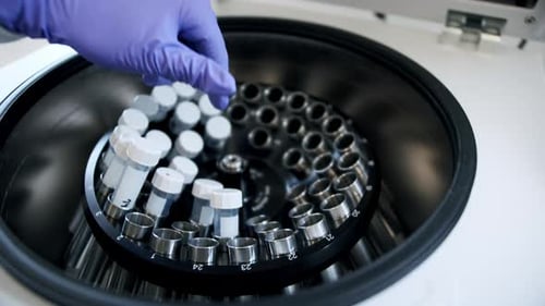 Scientist Loading Test Tubes Into Centrifuge Machine