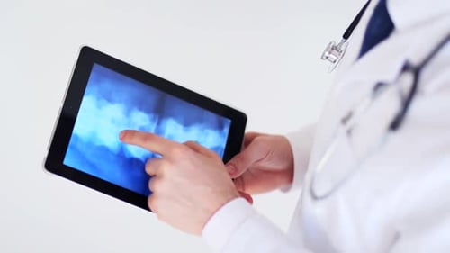 Professional doctor analyzing x-ray scan on tablet pc in modern hospital lab