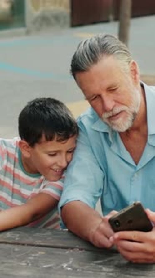 Grandfather and Grandson Looking at Phone Together