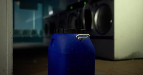 Couvercle d'un contenant bleu dans une laverie automatique en fin de soirée