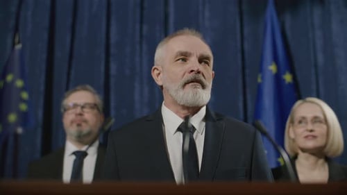 Man Giving Press Conference with European Union Flags