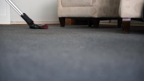 Vacuuming Gray Carpet Under Armchair
