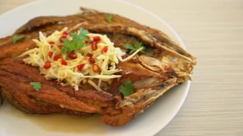 Fried Sea Bass Fish with Fish Sauce and Spicy Salad on plate