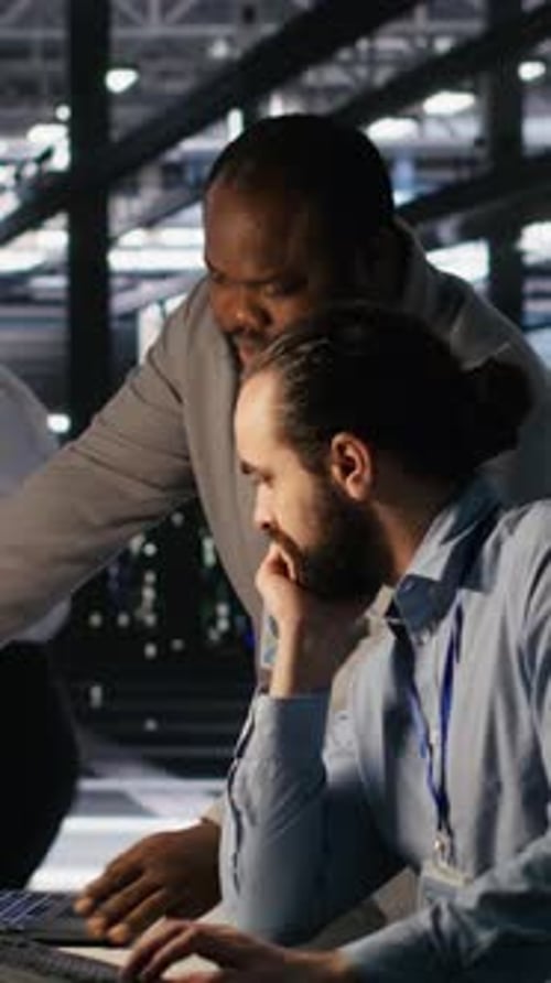 Vertical Video Data Center Engineers Use Laptop Collaborating on Doing AI Software Updates