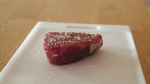 Raw Steak with Salt Being Prepared for Cooking