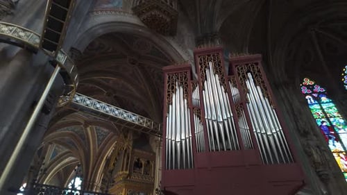Ornate pipe organ and colorful stained glass windows inside Votive Church, Vienna, Austria