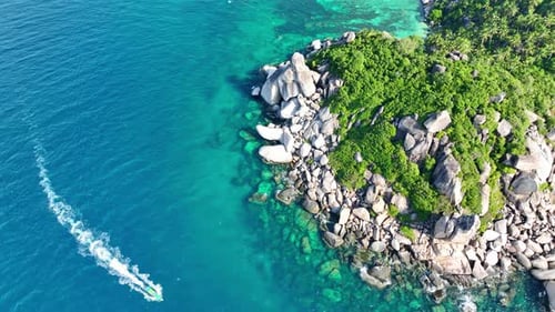 Top view of the boat moving along the rocky coast and green forest. 4K.