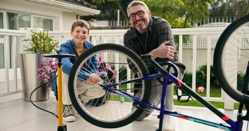 Child and Adult Kneeling around Bicycle on Porch
