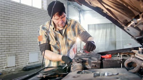 Car Mechanic Working on Engine in Auto Repair Shop