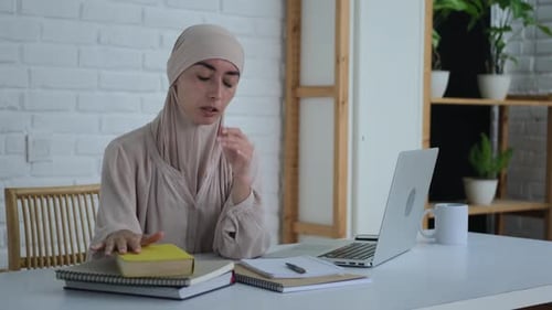 A Young Beautiful Woman in a Hijab is Studying at the University Getting a Higher Education