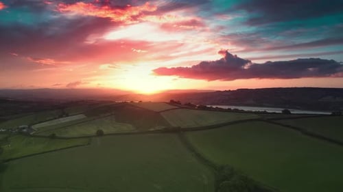Inspiring Pink and Orange Sunset or Sunrise Over Green Fields Near a River Aerial View