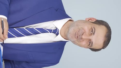 Smiling Businessman Signs Document on Blue Clipboard