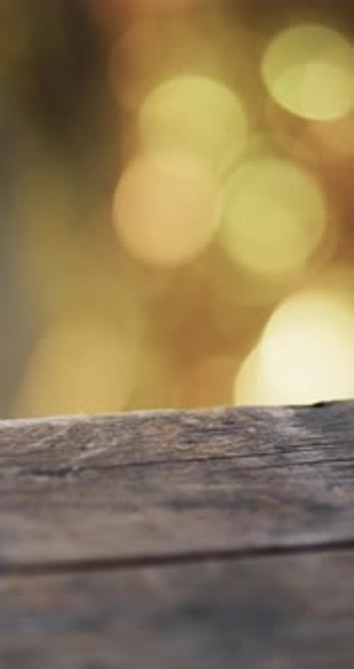 Vertical video of flickering yellow bokeh spots of light with copy space and wooden surface