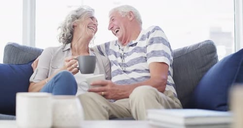 Senior Couple Laughing Affectionately on Couch Together