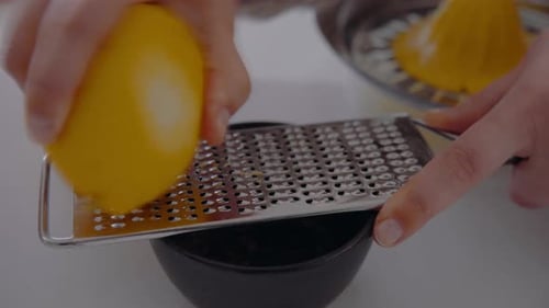 Küchenchef Reibt Zitronenschale mit einer Reibe in eine kleine Tasse