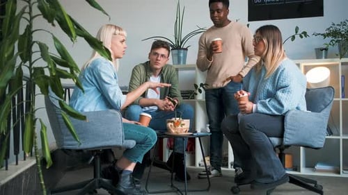 Diverse group of young business people taking during brake time while sitting in modern office.
