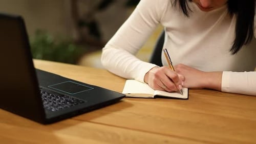 Femme prenant des notes à la main dans un bloc-notes, mains féminines écrivant