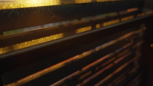Sunlight shining through the cracks of mechanical window blinds or shutters as they roll down during