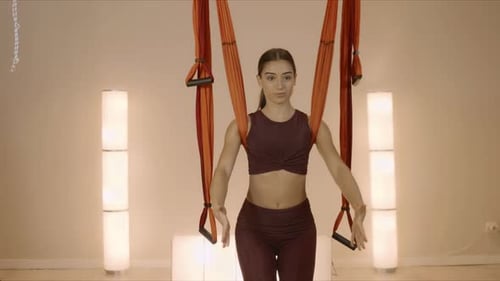 Cheerful woman stretching hands at yoga class with hammock in fitness studio