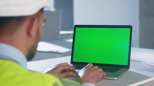 Engineer using Laptop Computer with Green Screen inside Building Under Construction. Great for Mock