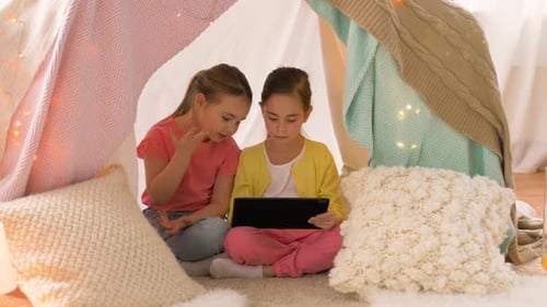 Two Girls Playing Together Using Tablet in Tent