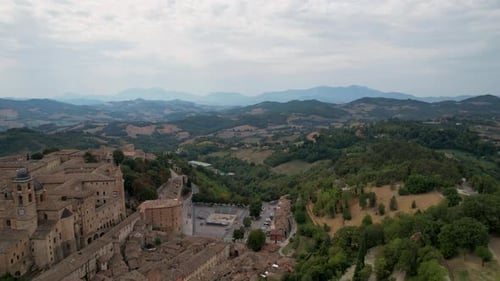 Aerial footage of the historic buildings of Urbino, Italy, surrounded by the picturesque rolling hil
