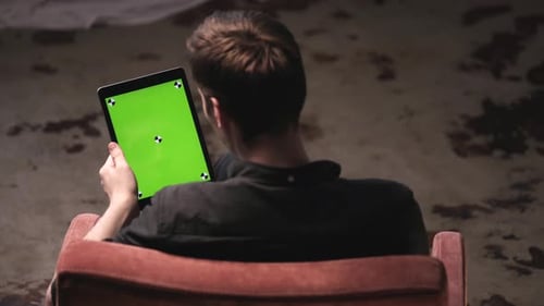 Man Sitting on Armchair Using Tablet with Green Screen