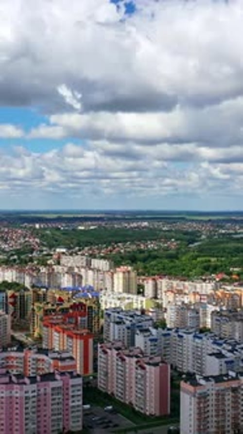 Urban background under beautiful sky. Modern city with high-rise buildings on green fields