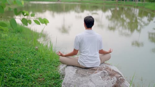 Power from within you serenity of meditation A young man is meditating on a large rock by the water