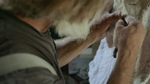 Sculptor Carving Ceramic Statue with Knife in Workshop