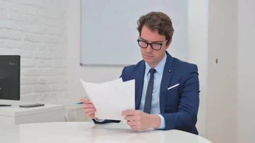 Man Reviews Documents at Office Desk