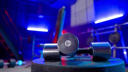 Silvery Metal Dumbbells Lying on a Blurred Background of an Empty Gym