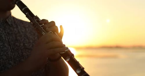 Man Plays Clarinet at Beach During Golden Hour