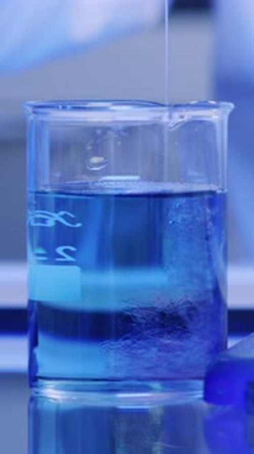 Blue Liquid Being Poured into Glass Beaker