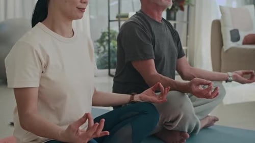 Couple Meditating Together on Yoga Mats at Home