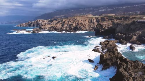 Bird's Eye View of Ocean Waves Crashing Against Stone Cliffs on Tenerife Island