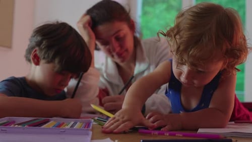 Mother and Children Drawing Together at Table Indoors