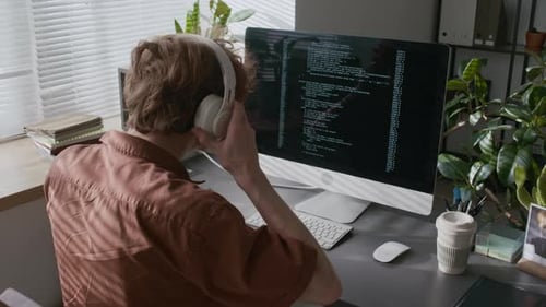 Young Adult Coding at Computer in Home Office