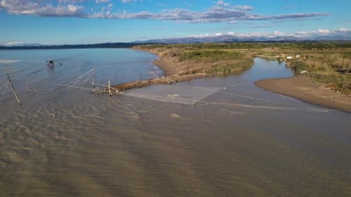 Large fishing nets hang over the mouth of the river where it joins the sea water