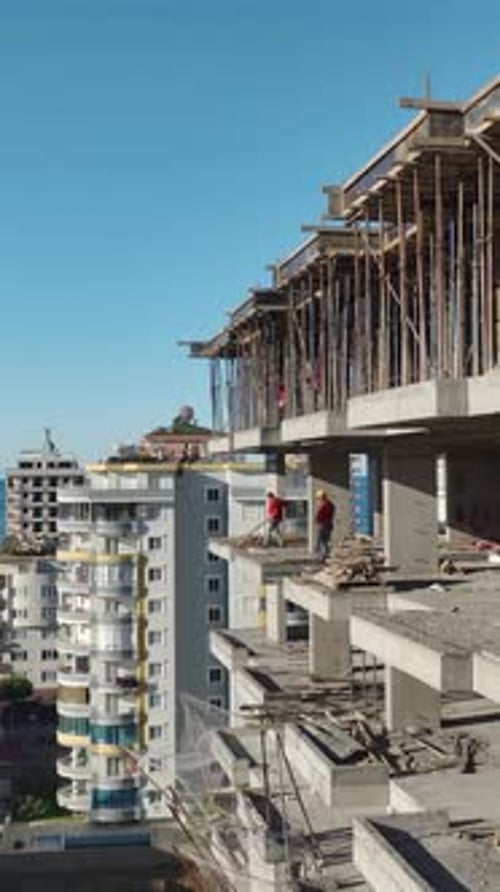 Vertical Video High Rise Concrete Building Under Construction with Crane and Surrounding Residential