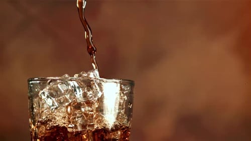 Brown Liquid Poured into Glass with Ice