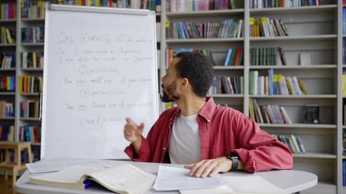 Multiethnischer männlicher Lehrer schaut in die Kamera, während er den Unterricht erklärt
