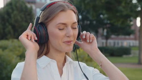 A Closeup of Young Woman Using Headphone for Listening Nice Music and Walking in City Girl Happiness