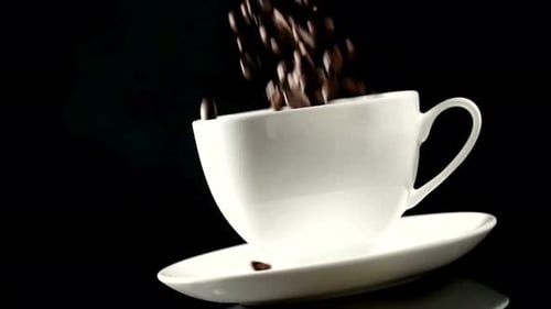 Coffee Beans Falling Into White Cup on Saucer
