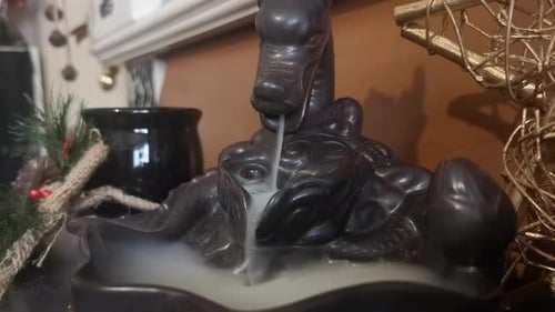 Backflow dragon incense burner pouring mystical smoke flowing fountain close up