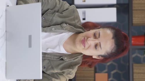 Woman Smiling While Working on Laptop at Desk