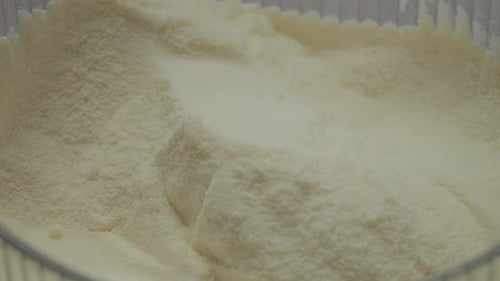 Powdered milk falls gracefully into a container in close-up view