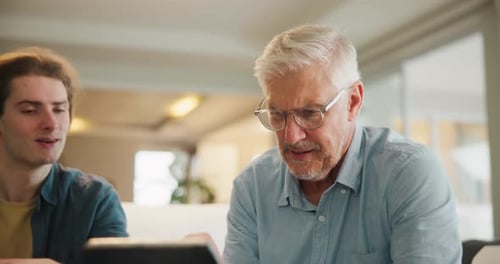 Senior Man Using Tablet with Young Adult