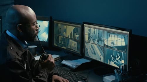 Man Monitoring Security Cameras in a Dark Room